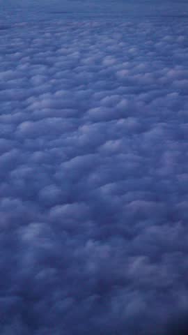 Aerial view from an airplane window flying over a sea of clouds above bogota, colombia at dusk