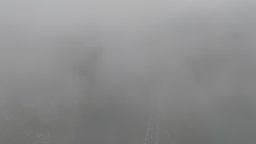 Aerial view of winding road through dense fog at Fluela Pass in Zernez, Grisons, Switzerland.
