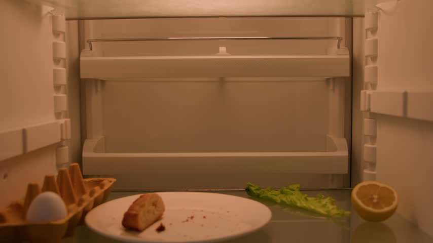 Confused Caucasian hungry man opening empty refrigerator eating crumbs needing food products POV inside fridge male guy with lemon lettuce egg bread juice bottle ordering delivery problem solution