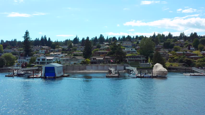 Scenic waterfront properties along Indian Arm near Vancouver, British Columbia, Canada. Beautiful homes nestled among lush evergreen trees overlook calm blue ocean waters, with private docks, floating boathouses, and boats along the shoreline. A peaceful coastal residential setting surrounded by the natural beauty of the Pacific Northwest.