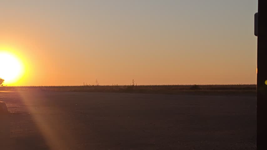 A car drives along the road at sunset.