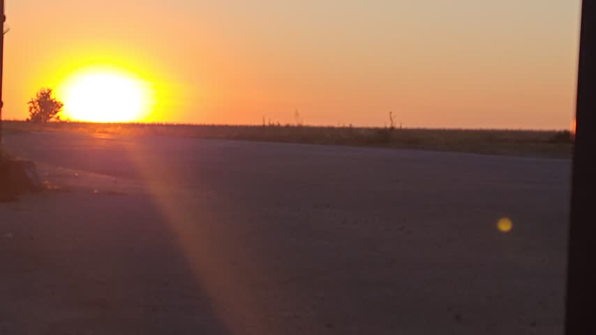 A car drives along the road, heading toward the sunset.