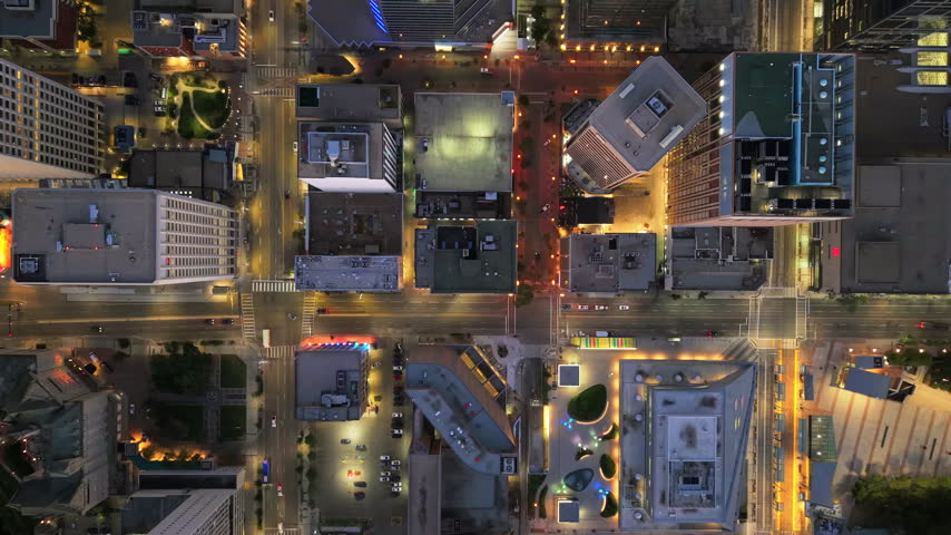 Vertical drone flight above downtown Edmonton during blue hour, showing illuminated rooftops, intersections, moving cars and the precise geometry of the city grid.