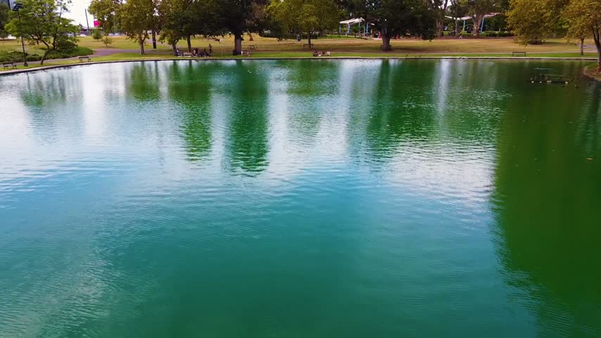 Aerial view of Rymill Park lake in Adelaide, featuring lush green trees, calm water, and park grounds in Adelaide, South Australia, Australia.