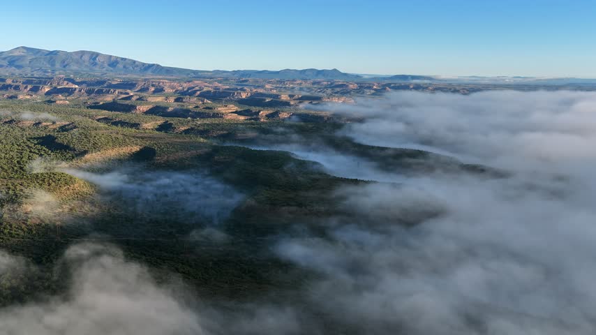 Aerial view of a sea of fog rolling over a mesa landscape in the high desert of White Rock, New Mexico, United States.