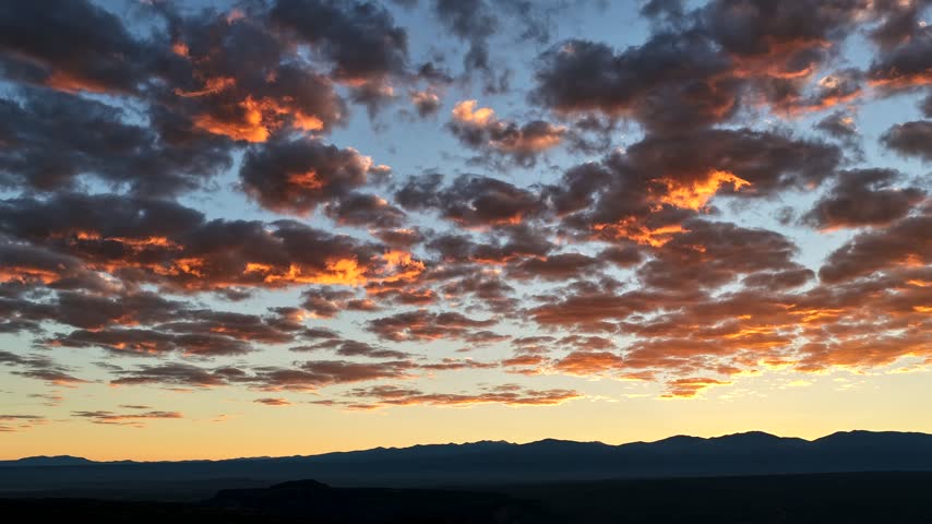 Aerial view of golden clouds moving towards Mt Baldy at sunrise over the landscape in White Rock, New Mexico, United States.