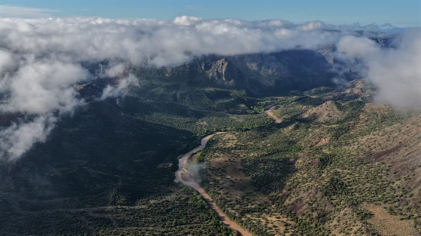 Aerial view of the Rio Grande valley with dense fog rolling over the rugged landscape in White Rock, New Mexico, United States.