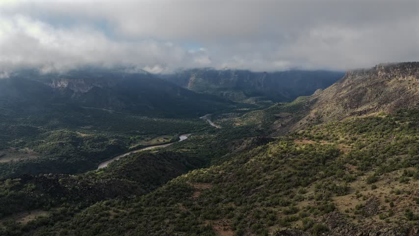 Aerial view of Rio Grande valley with low clouds and fog over green hills in White Rock, New Mexico, United States.