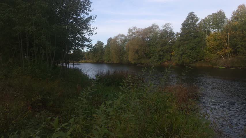 Wide flowing river bend, autumn trees backdrop 