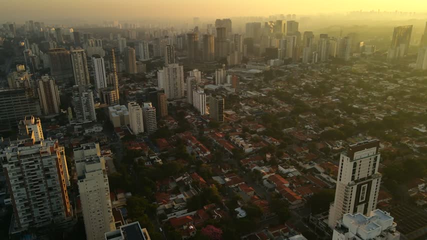 Aerial view of the dense urban skyline and residential rooftops bathed in golden hour light in Sao Paulo, Sao Paulo, Brazil.