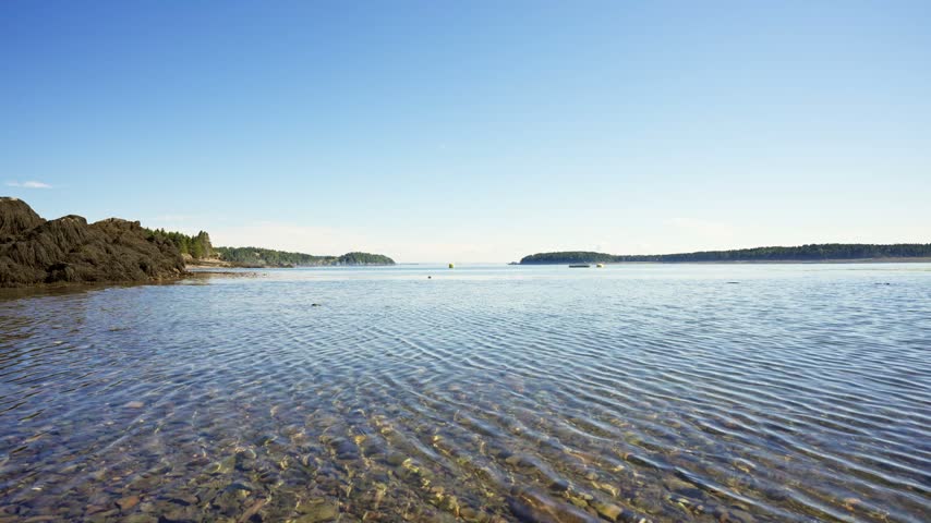 Clear shallow coastal waters rippling over a pebbled shoreline along Passamaquoddy Bay in Deer Island, New Brunswick.