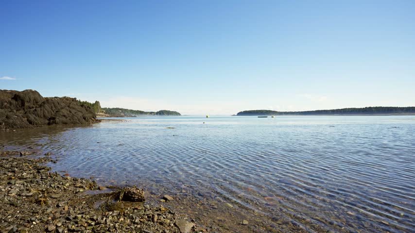 Clear shallow coastal waters rippling over a pebbled shoreline along Passamaquoddy Bay in Deer Island, New Brunswick.