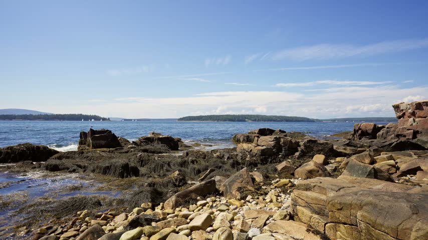 Granite boulders and cobble shore along Schoodic Peninsula looking out across Frenchman Bay toward Mount Desert Island in Acadia National Park, Maine.