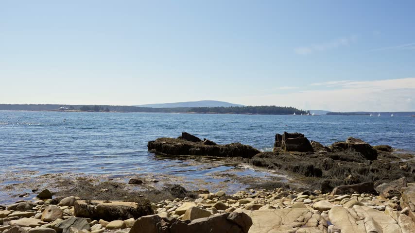 Granite boulders and cobble shore along Schoodic Peninsula looking out across Frenchman Bay toward Mount Desert Island in Acadia National Park, Maine.
