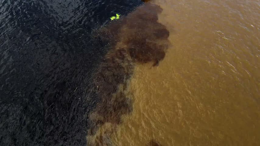Aerial view of the confluence of the dark Rio Negro and sandy Solimoes River in Manaus, Amazonas, Brazil.