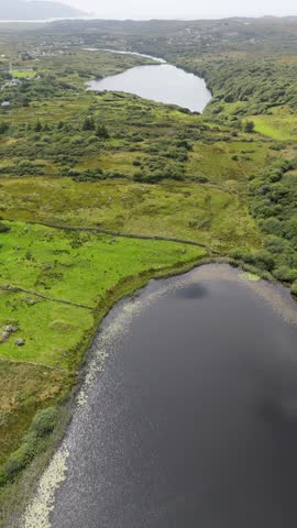 Aerial view of Bonny Glen Woods featuring lush green fields, stone walls, and tranquil lakes in Portnoo, County Donegal, Ireland.