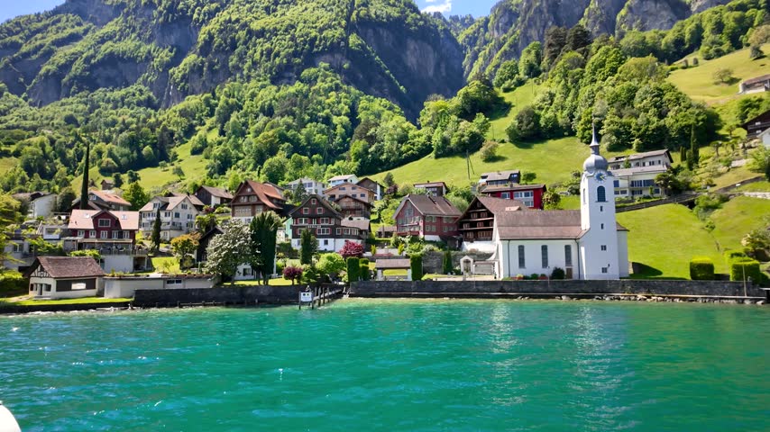Picturesque Swiss village with a church on the shore of a beautiful turquoise alpine lake.