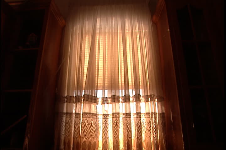 Curtains blowing in breeze from broken window, camera tilts down to kitchen sink filled with silt and debris in New Orleans after Hurricane Katrina (October 2005).