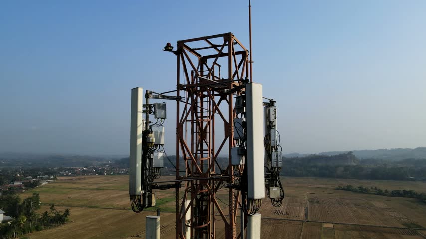Aerial view of a telecommunications tower rising above rural fields in Patikraja, Central Java, Indonesia.