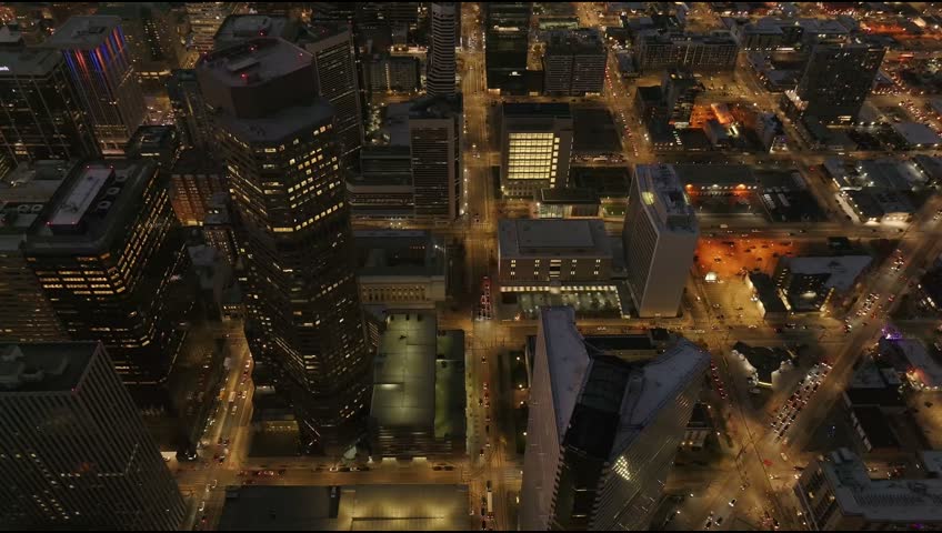 Aerial view of the illuminated Denver city skyline at night, featuring skyscrapers, grid streets, and glowing urban lights in Denver, Colorado, United States.