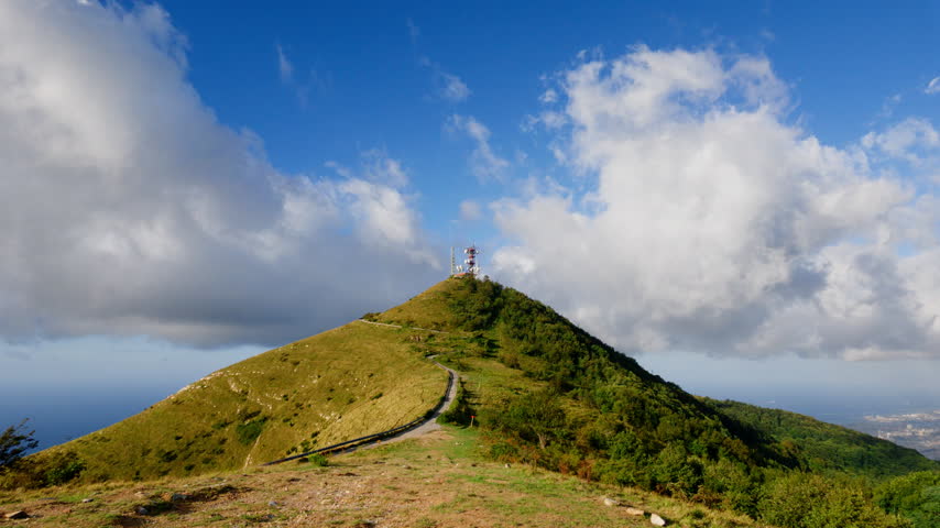Scenic view of green lands mountain peak and blue sky with clouds