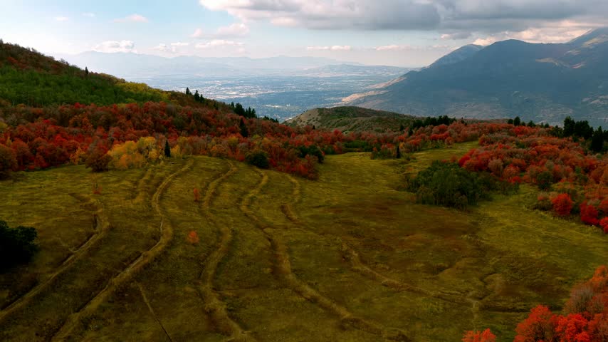Aerial view of the Wasatch Range mountains featuring vibrant autumn foliage and rolling hills above Provo, Utah, United States.