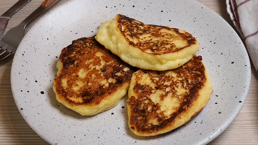 Cottage cheese pancakes on a plate are topped with sour cream. Fried cheesecakes with smetana.