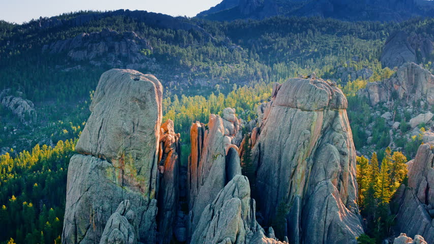 Aerial cinematic shot of fascinating rock formations surrounded by the wild landscape of South Dakota.