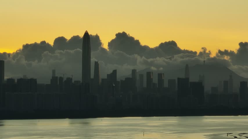 Elevated view of tall tower silhouetted against layered morning clouds in Shenzhen, Guangdong, China. The scene features Ping An Finance Centre. Relevant to architecture and urban planning.