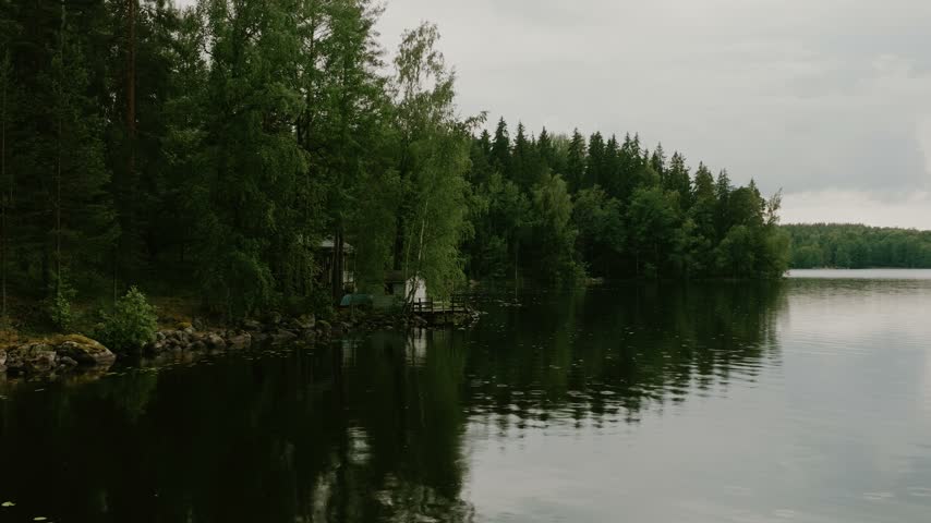 Aerial view of the lush forest shoreline and calm lake waters in Hameenlinna, Kanta-Hame, Finland.