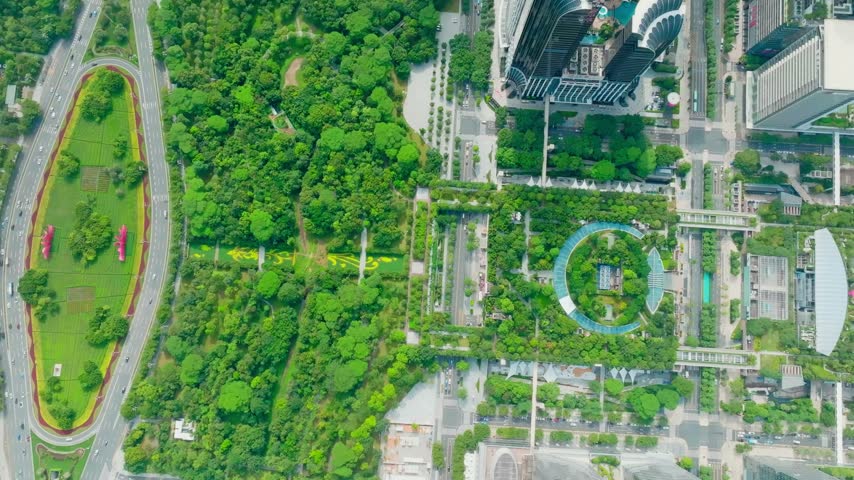 Overhead view of oval green median beside civic plaza geometry in Shenzhen, Guangdong, China. The scene features Shenzhen Civic Center. Relevant to architecture and urban planning.