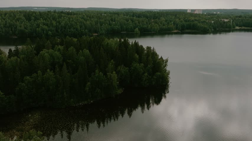 Aerial view of a calm lake surrounded by dense pine forests in Hameenlinna, Kanta-Hame, Finland.