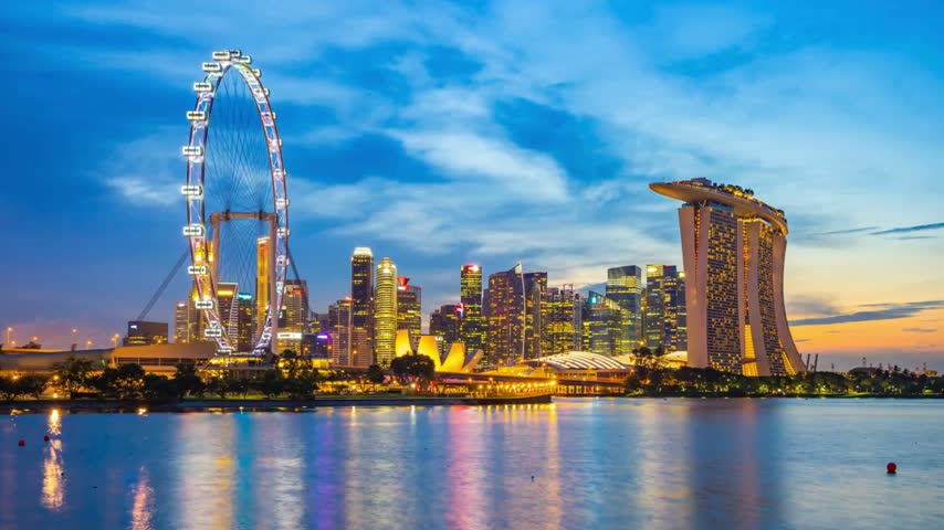 Night-to-day time-lapse of Singapore’s downtown district, capturing the transformation from illuminated city skyscrapers and vibrant nighttime streets to the bright morning skyline, showcasing modern architecture and the dynamic urban landscape.