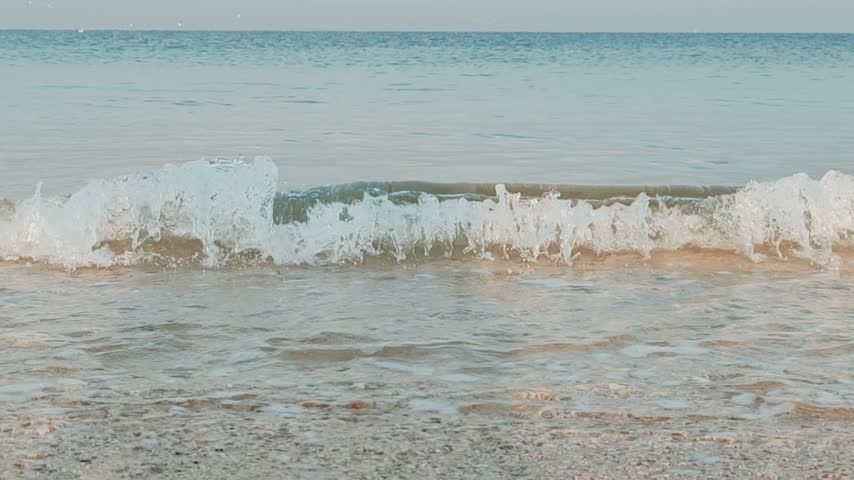  Powerful ocean waves crashing forcefully against the shoreline, creating a dramatic scene of natural beauty and untamed energy. The roaring waves rise high above the sea surface before rushing toward the beach, forming thick layers of white foam and sparkling sea spray. As the water strikes the shore, it spreads rapidly across the wet sand and then retreats into the ocean, leaving behind swirling patterns of foam. The stormy sea appears rough and restless, with waves continuously building, breaking, and colliding against one another. The deep blue and grey tones of the water create a striking contrast with the bright white froth along the wave crests. The powerful movement of the ocean highlights the immense strength of nature and the endless rhythm of the tides.