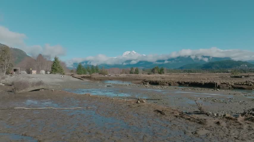 Aerial drone footage flying over the Squamish estuary and marshlands toward snowcapped Atwell Peak and the Mount Garibaldi massif in British Columbia Canada