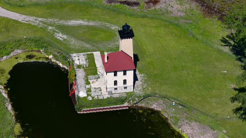 Saginaw river range Lighthouse standing by a winding channel, surrounded by green trees and grass by Lake Huron.