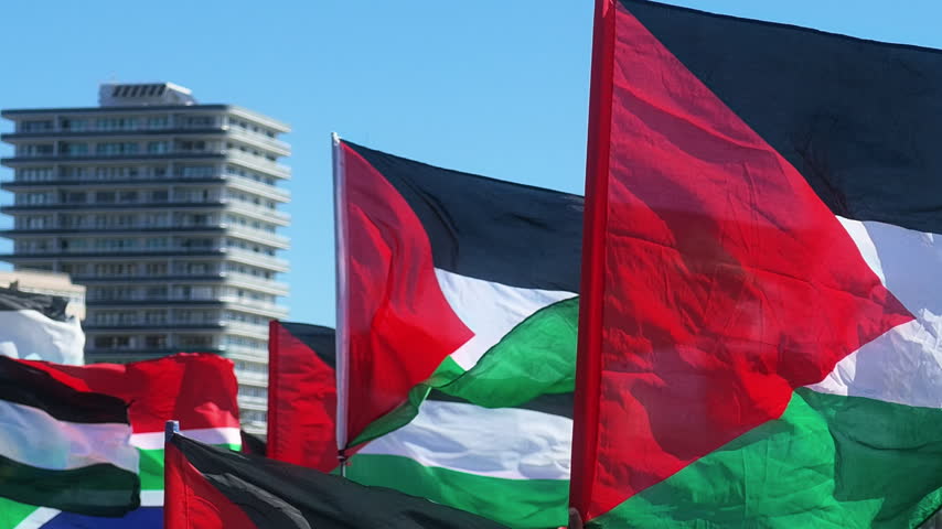 Palestinian flags waving alongside South African flags in slow motion during a protest rally in Cape Town, South Africa