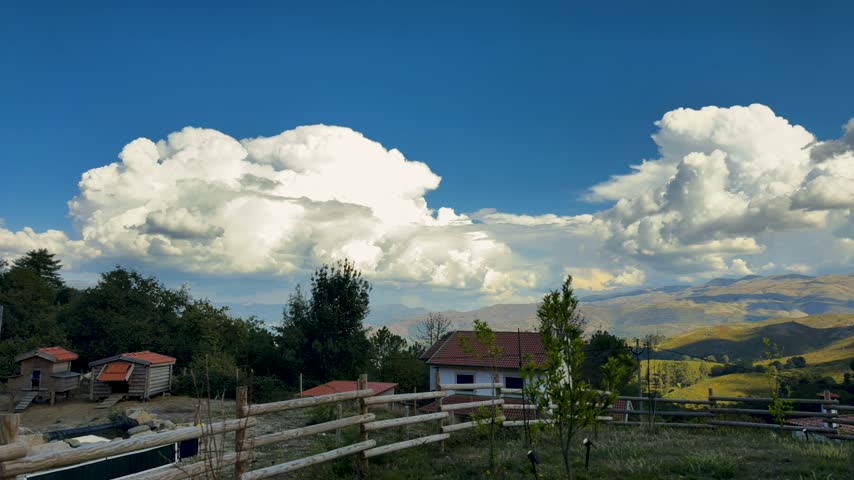 A dramatic time-lapse film clip captures towering cumulus clouds expanding over a remote mountain farm.