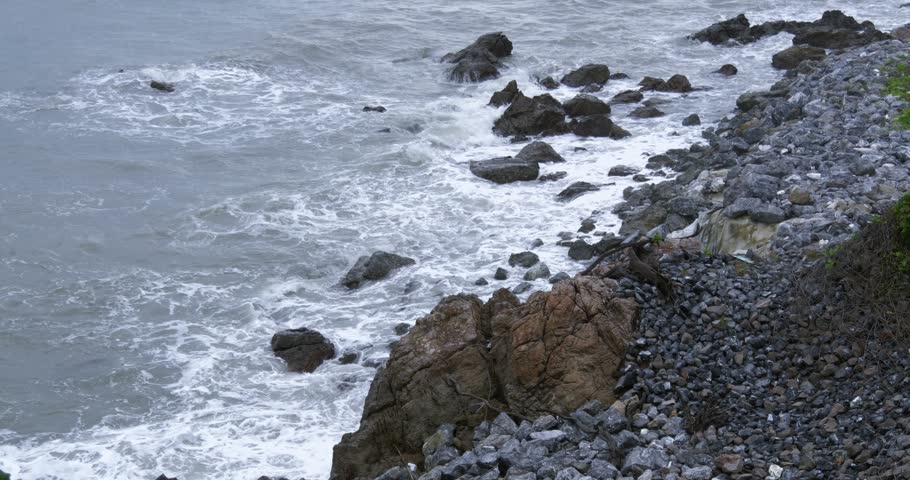Rocky coastal landscape with gentle waves washing over stones during dusk