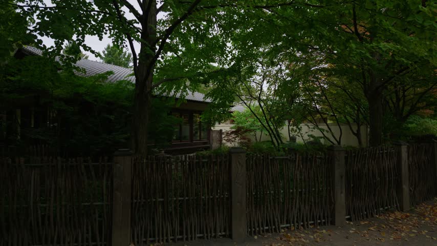 Montreal Botanical garden Japanese garden with stone lantern, wooden fence, traditional house and maple trees, slow push in, calm zen nature atmosphere, Quebec, Canada.