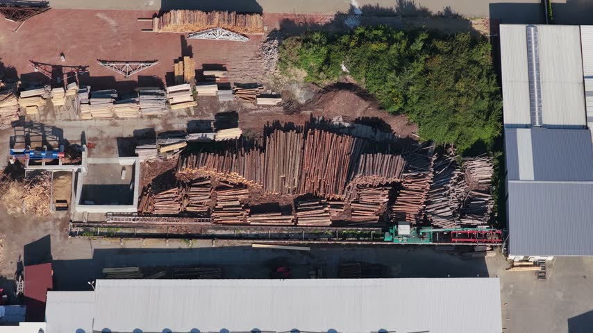 Industrial sawmill yard with stacked timber logs and lumber processing equipment, aerial view