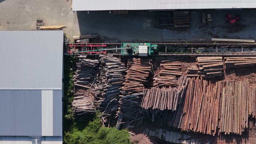 Top-down aerial view of a lumber yard with log piles and processing equipment at a sawmill