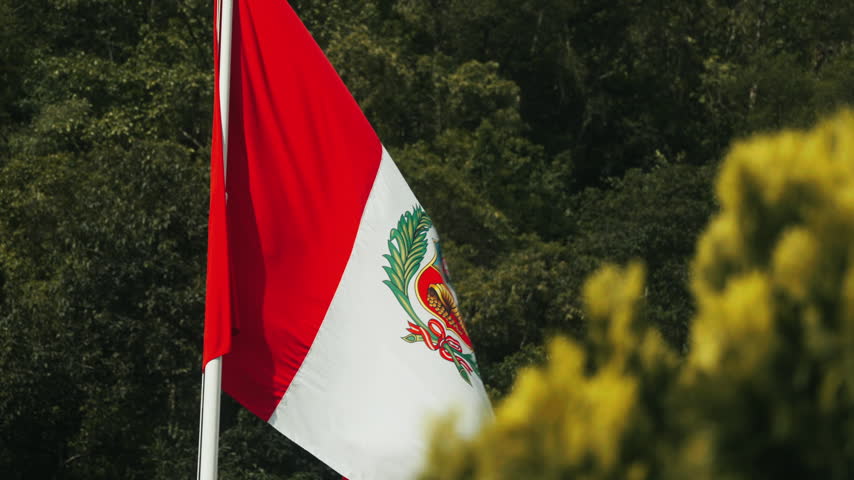 Cinematic close-up of the red and white national flag of Peru waving against the Andean landscape