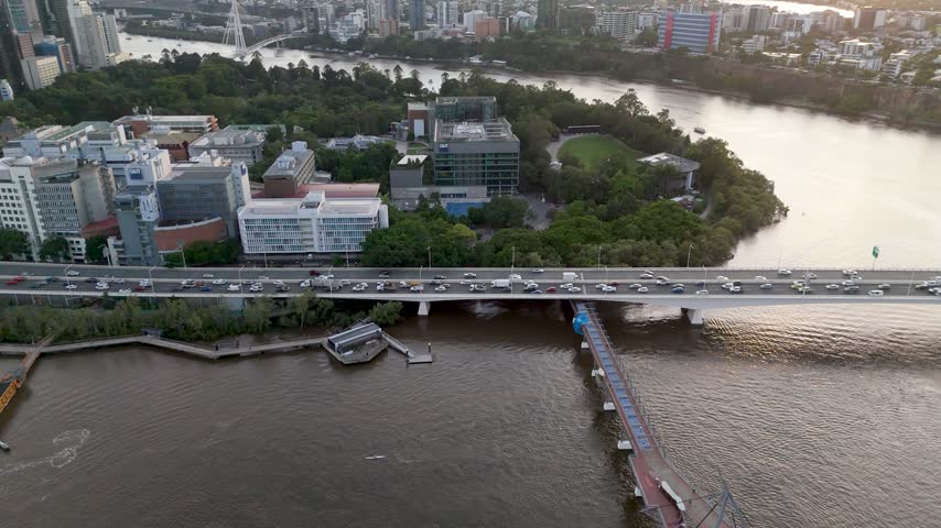 Aerial tracking shot of the Brisbane CBD skyline, Brisbane River, and morning rush hour expressway traffic with ferry boat in Queensland, Australia.