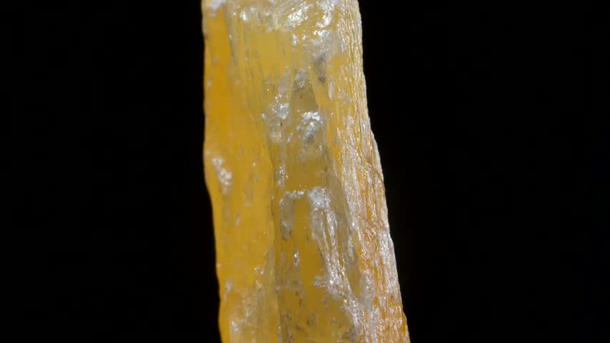 Yellow Calcite crystal sample rotating slowly against a black background