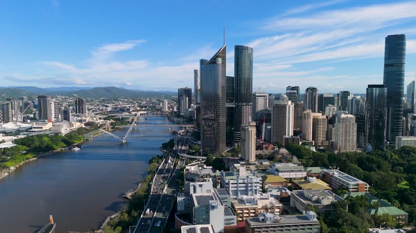 Aerial drone forward flight approaching the Brisbane CBD skyline and Brisbane River in bright morning light in Queensland, Australia.