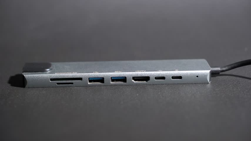 Multiport USB-C Hub Adapter with Ethernet and HDMI Ports .
A multiport USB Type C hub adapter featuring SD card slots, USB 3.0, HDMI, and Ethernet ports isolated on a dark background for PC and Laptop connectivity.