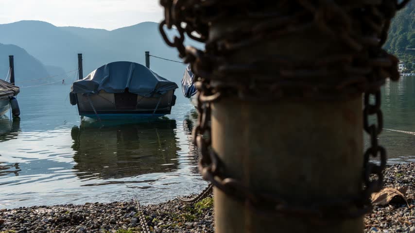 A timelapse of small boats bob while moored at the shore of Lake Lugano in Caslano.