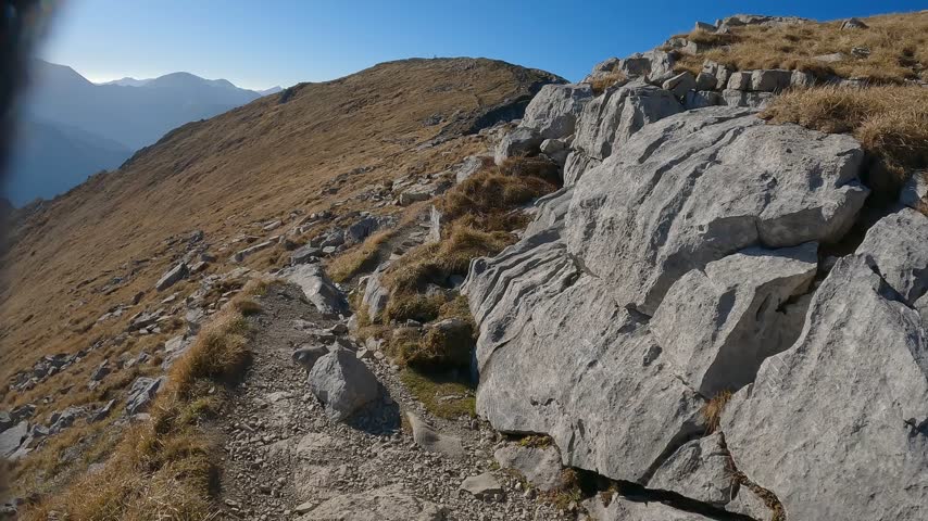 Dry highland grass surrounds a rocky trail on the route from Krzesanica to Ciemniak