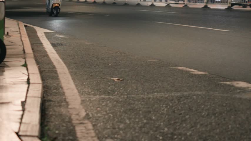 Nighttime street scene in Tokyo, Japan with motorcycles on asphalt road and curb details under artificial lighting